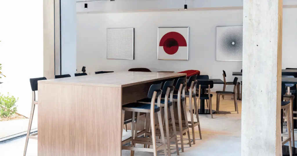 Collaborative hot desk workspace at Strive Coworking Workspaces with a shared wood table, high seating, and modern design.
