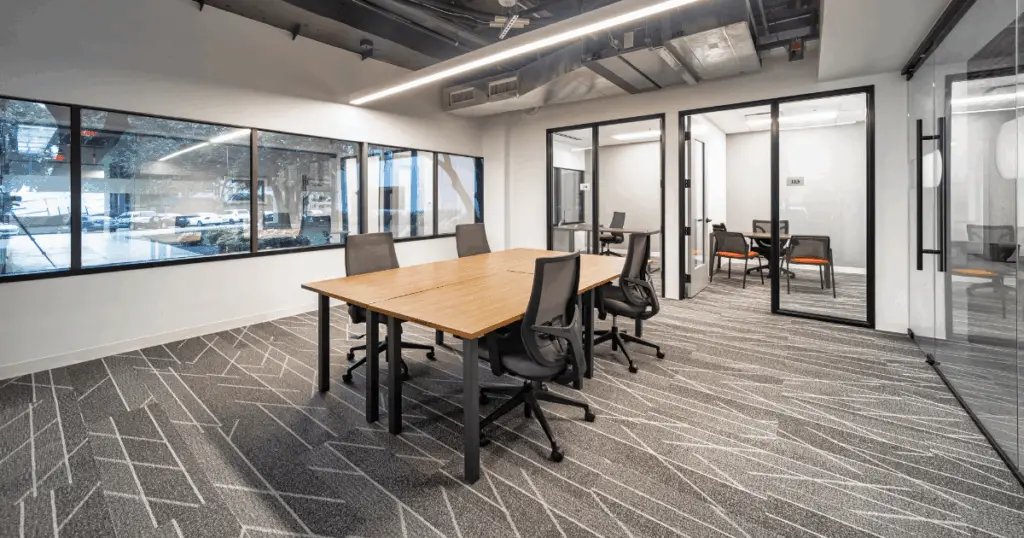 Team private office at Strive Coworking Workspaces with a shared work table, ergonomic seating, and adjacent enclosed offices.
