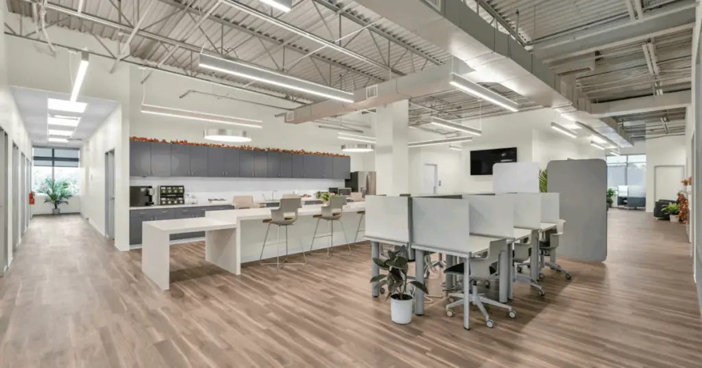 Open coworking area with shared desks and kitchen at Strive Coworking Workspaces in Cypress, Texas