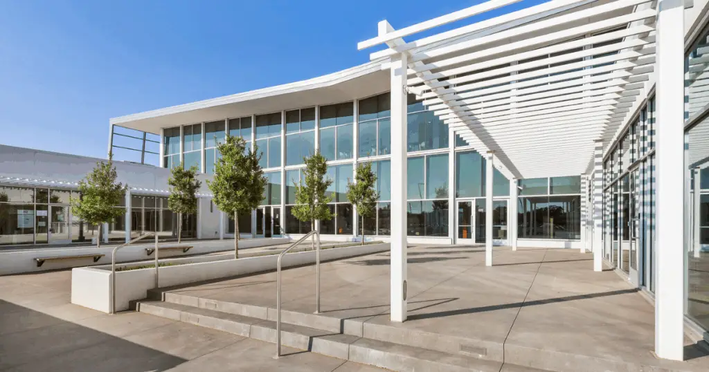 Exterior view of Venture X Braniff Centre coworking space in Dallas, Texas, featuring modern glass architecture and shaded outdoor walkways.