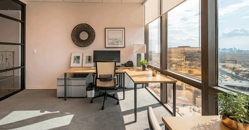 Private office at Strive Coworking Workspaces with a furnished desk, storage, and large windows offering city views.