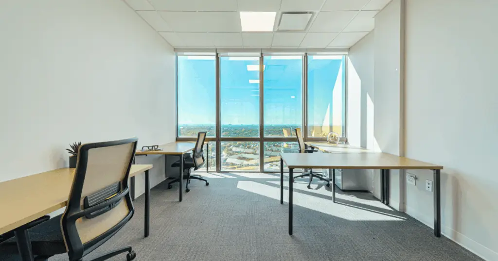 Private office at Flex at The Gild by Strive Coworking Workspaces featuring modern desks, ergonomic chairs, and floor-to-ceiling windows with city views.