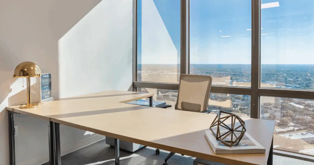 Private office at Flex at The Gild by Strive Coworking Workspaces with furnished desk, modern decor, and floor-to-ceiling windows overlooking Dallas.