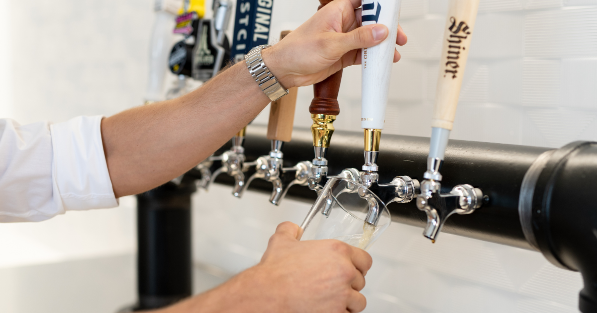 Image features client using the beer tap at a coworking space. 