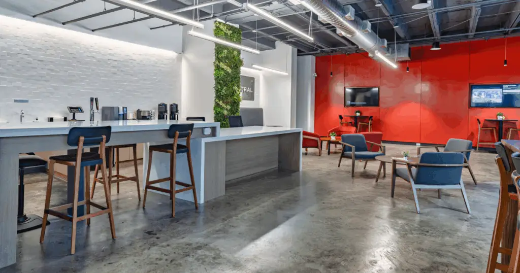 Event space at Strive Coworking Workspaces with a modern lounge layout, bar seating, presentation screens, and flexible gathering areas.