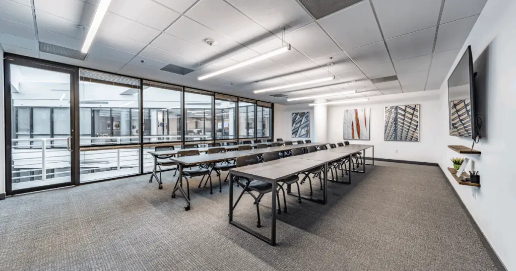 Training room at Strive Coworking Workspaces with long tables, classroom seating, and AV display.