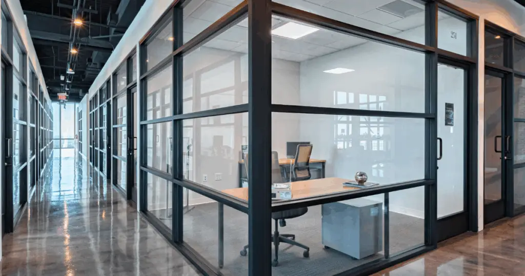 Glass-walled private offices at Flex at The Gild in Dallas, Texas, featuring modern workstations and a polished corridor.