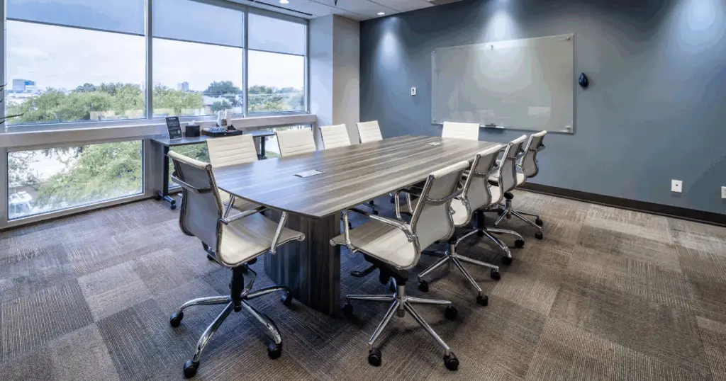 Conference room in North Dallas at Strive Workspaces featuring large meeting table, whiteboard, and floor-to-ceiling windows.