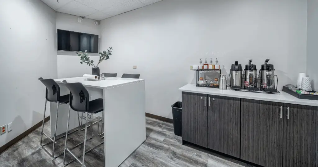 Breakroom and coffee station at Strive Workspaces North Dallas featuring refreshments and communal seating.