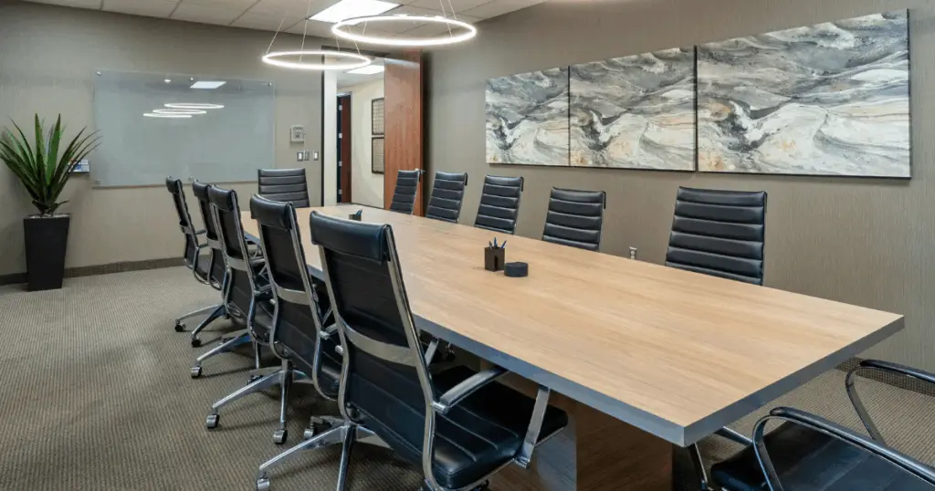 Spacious meeting room at Strive Coworking Workspaces with large conference table, ergonomic chairs, glass whiteboard, and modern ring lighting.