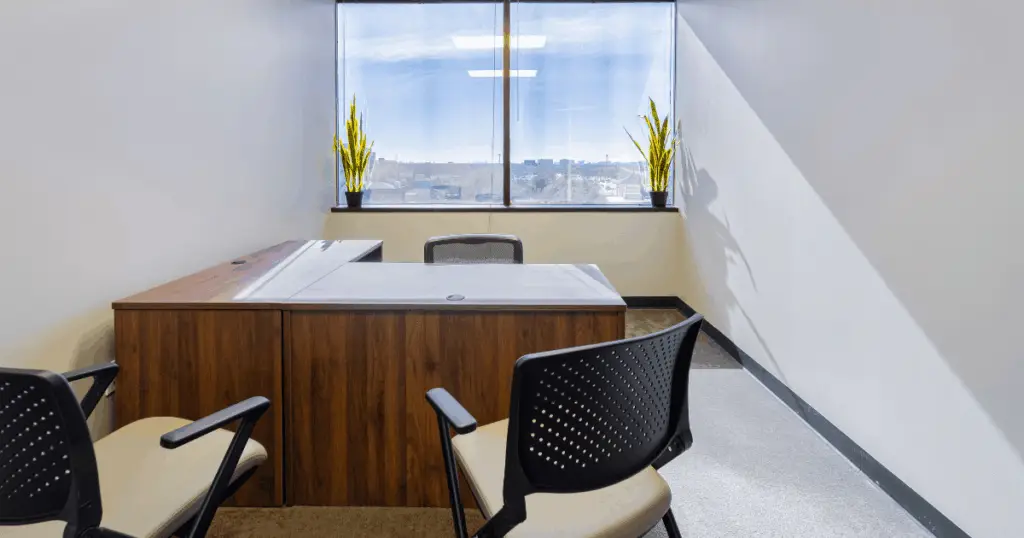 Private office at Strive Coworking Workspaces with an executive desk, guest seating, and natural light from a window.