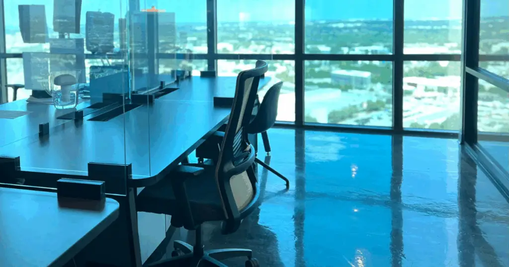 Dedicated desk workspace at Strive Coworking Workspaces with glass dividers, ergonomic seating, and floor-to-ceiling windows overlooking the city.