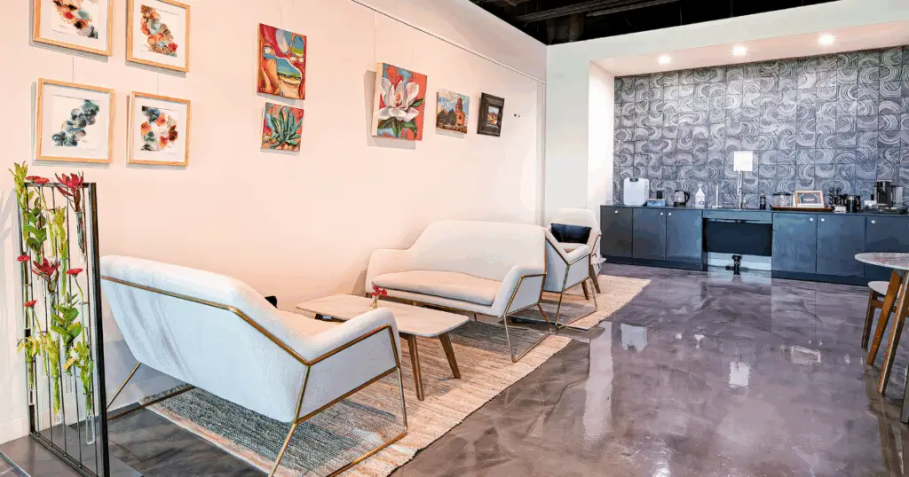 Coworking lounge and coffee bar at Flex at The Gild in Dallas, Texas, featuring modern seating, wall art, and a refreshment area.