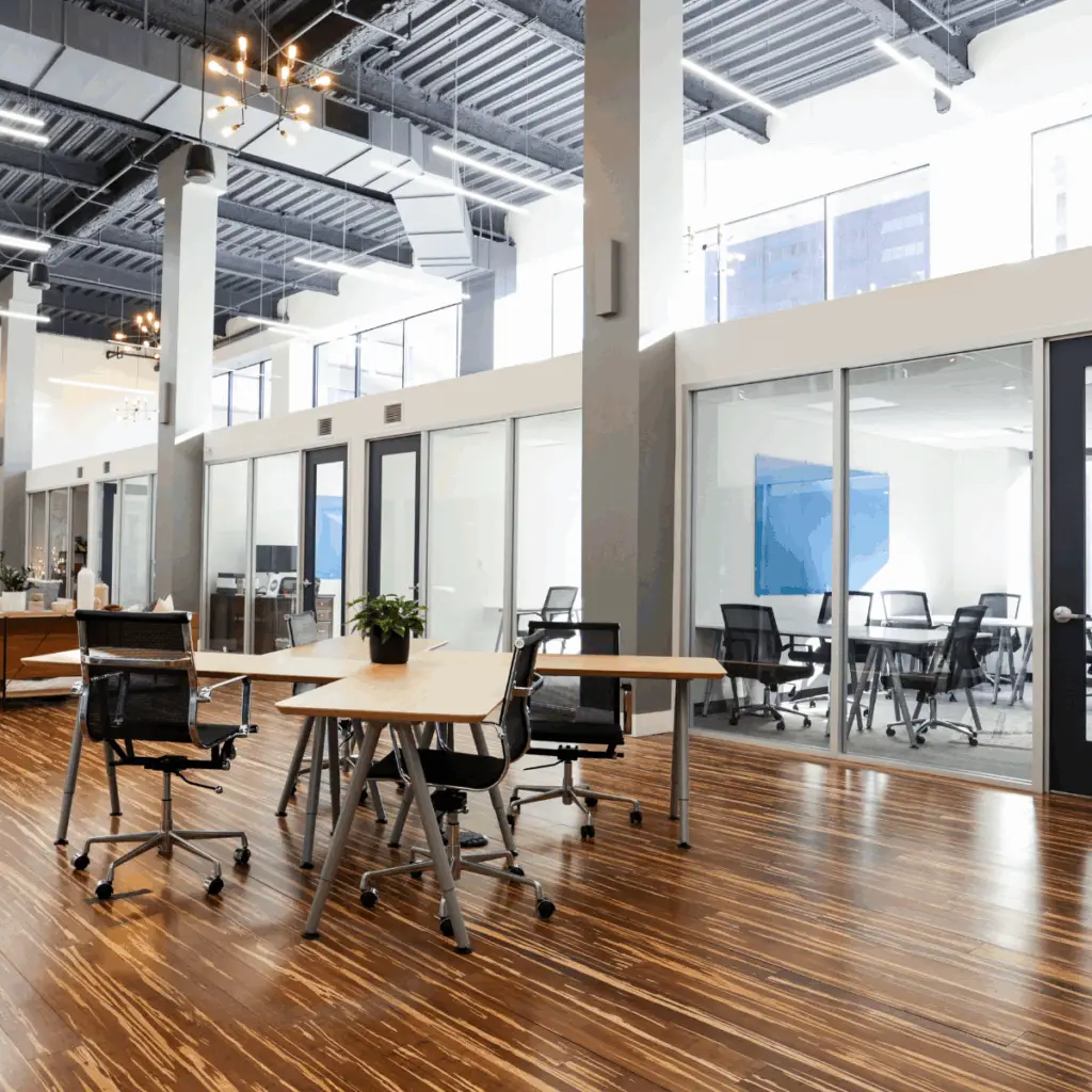 Shared coworking area with tables and glass-walled meeting rooms available to virtual office members at Strive Coworking Workspaces.