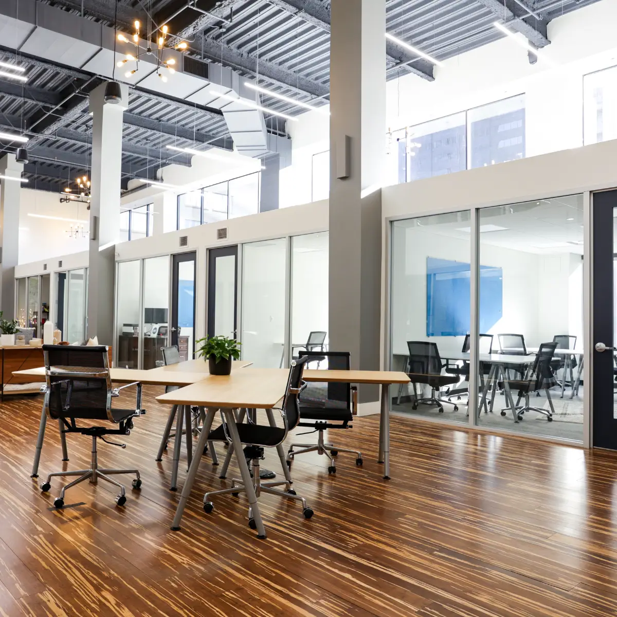 Shared coworking area with tables and glass-walled meeting rooms available to virtual office members at Strive Coworking Workspaces.